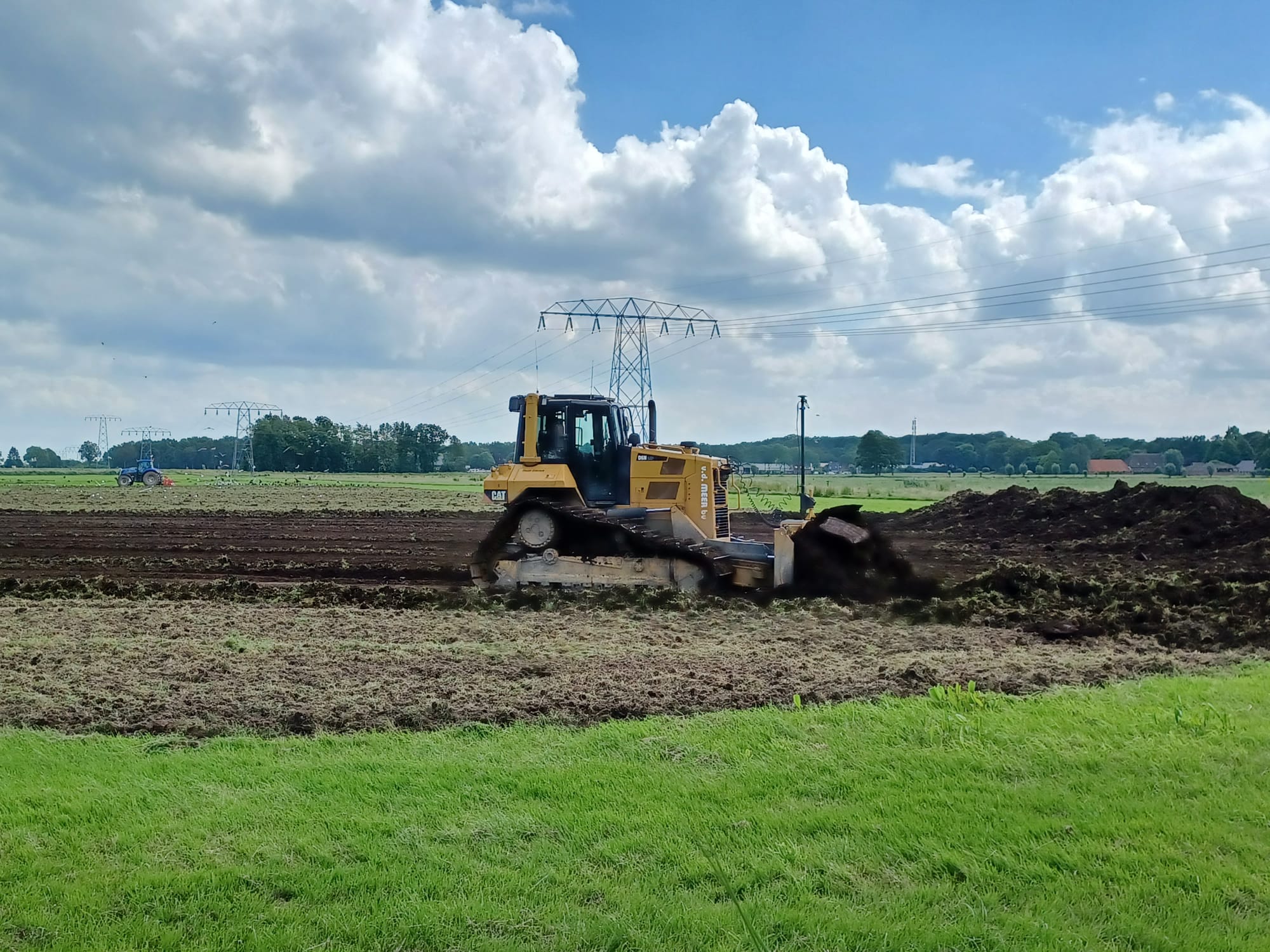 Een bulldozer schuift grond voor zich uit. Zo wordt grond weggehaald om een kade te plaatsen