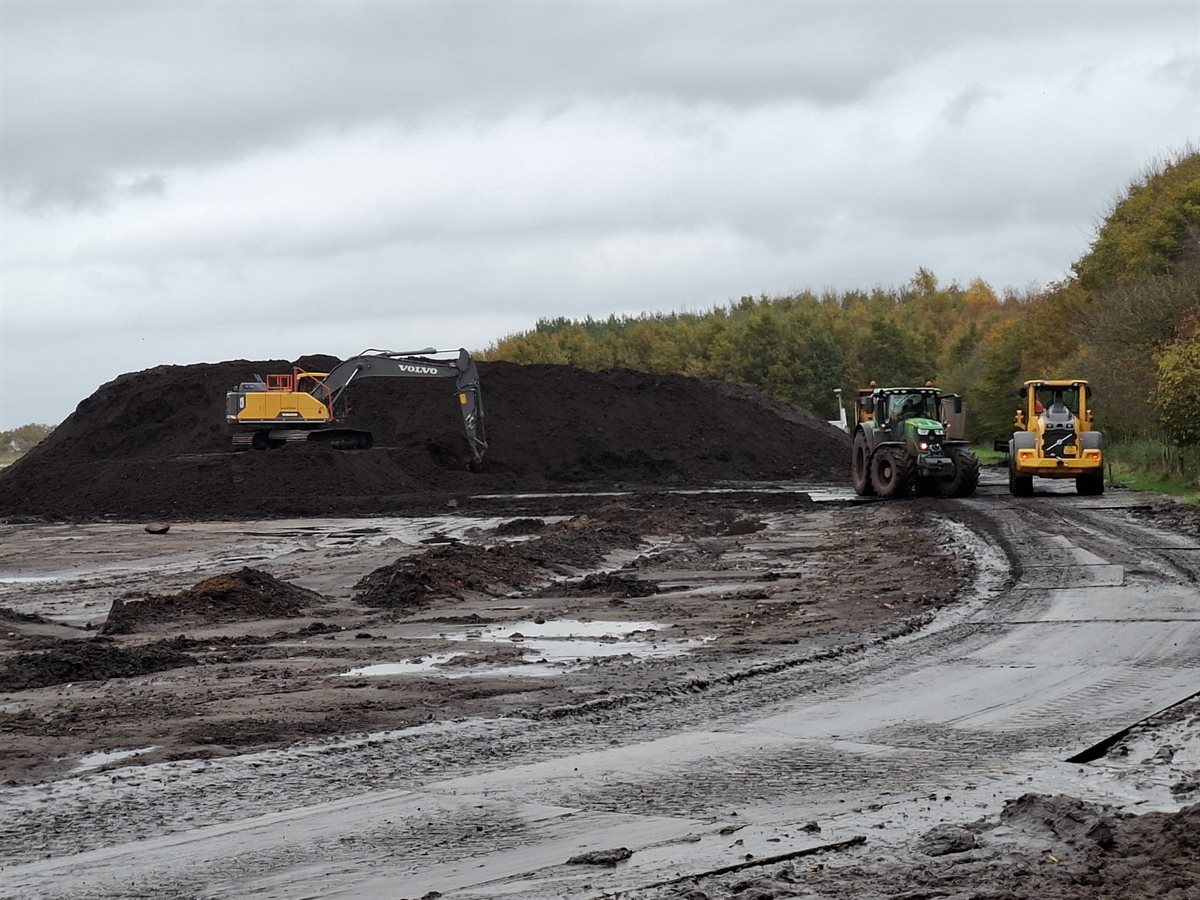 kraan, tractor en afvoerwagen rijden af en aan naar de tijdelijke grondopslag