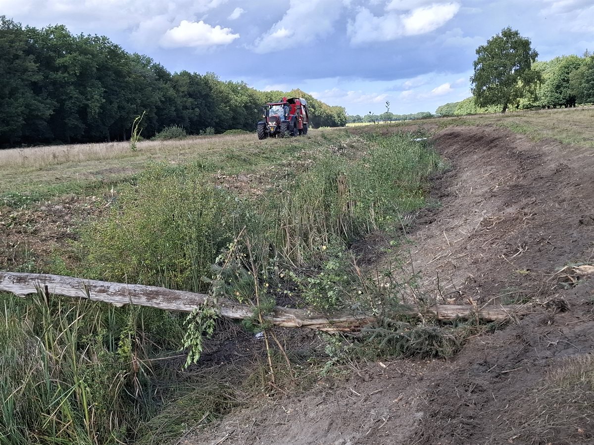 een tractor is aan het bosfrezen op het veld
